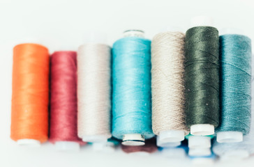 Colored sewing thread coils on white background with copy space for text.