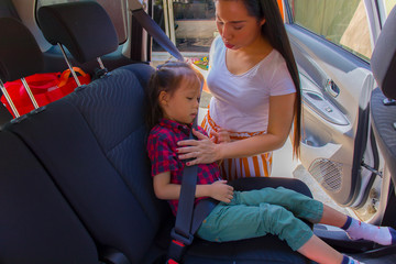 Mother buckling up safety bells for her children's on car seat.