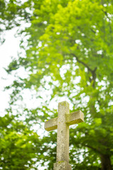 Jesus Christ cross in concrete with trees as background.