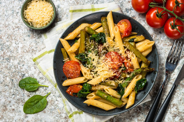Vegan pasta penne with spinach, asparagus and tomato.