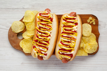 Homemade colombian hotdogs with pineapple sauce, yellow mustard and mayo ketchup on a rustic wooden board, top view. Flat lay, overhead, from above. Close-up.