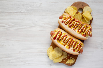 Overhead view, homemade colombian hot dogs with pineapple sauce, yellow mustard and mayo ketchup on a rustic wooden board. Flat lay, from above, top view. Copy space.