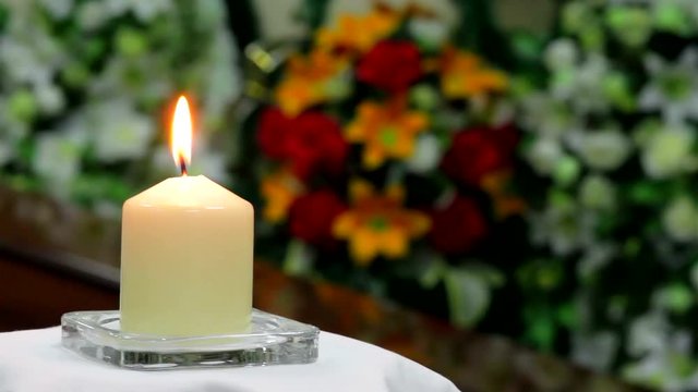 Сatholic candle burns on the background of mourning wreaths,