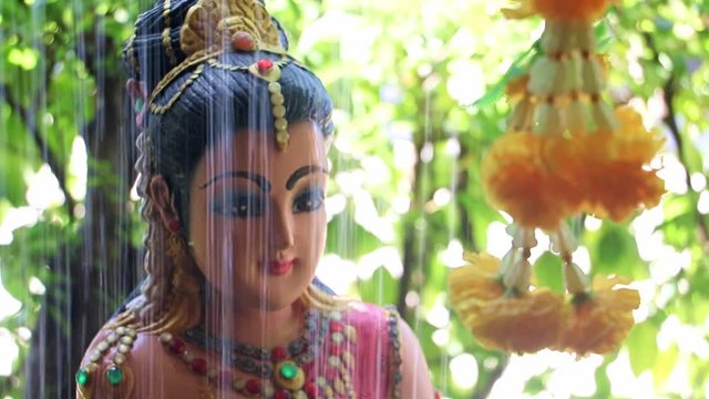 Phra Mae Thorani, goddess from Buddhist mythology, behind water of fountain.