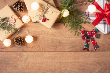 Christmas Background. Top View Of Christmas Boxes And Lights In Craft And Red Stripe Paper Decorated With Branch, Linen Cord, Red Bow On Wooden Table. Copy Space