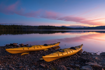 Two kayaks on the shore of a lake during a tranquil dusk. Jamtland, Sweden.