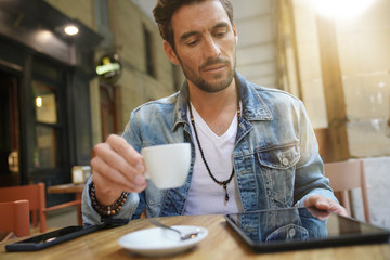 Fototapeta premium Trendy guy connected on tablet at coffee shop