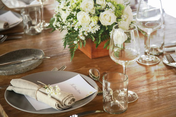 The beautiful arrangement on the wooden table, white roses and ceramic plates. Boho chic wedding table setting. 