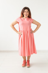 people, fashion and design concept - young woman posing in rose dress on white background.