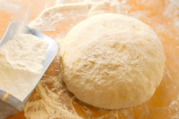 Dough on a wooden Board with a ladle for flour. Gentle dough for baking