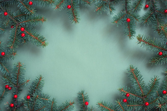 Christmas or New Year background with spruce branches on blue-emerald paper surface