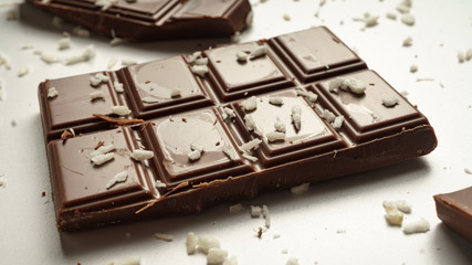 Pieces of chocolate and coconut crumbs against white background