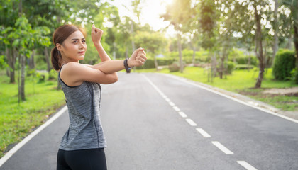 Fitness woman doing stretch exercise stretching her arms - tricep and shoulders stretch wearing a smartwatch activity tracker. Women stretching for warming up before running or working out.