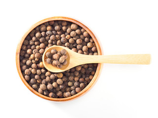 Allspice (Jamaica pepper) in wooden cup and spoon horizontally on white background