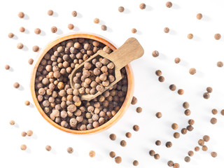 Allspice (Jamaica pepper) in wooden cup and scoop on white background