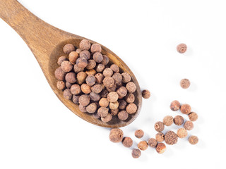 Allspice (Jamaica pepper) in the wooden spoon diagonally on white background