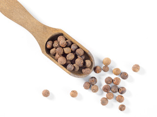 Allspice (Jamaica pepper) in wooden scoop diagonally on white background