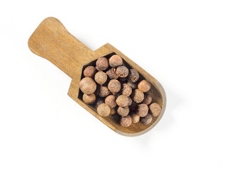 Allspice (Jamaica pepper) in wooden scoop diagonally on white background