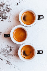 Three cups of freshly brewed espresso coffee on a textured table top with copyspace
