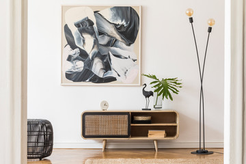 Stylish scandinavian living room interior with modern wooden commode, stylish lamps, plants, rattan basket, sculpture and elegant personal accessories. Mock up paintings on the white wall. Template. 