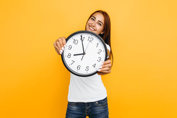 Young attractive woman with a watch on a yellow background