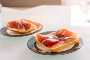 Two delicious homemade toast with serrano ham in different plates
