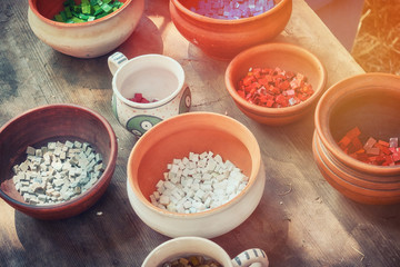 The material for decorating the walls of houses and dishes in ancient times, reconstruction. Retro mosaic cubes in clay pots. Creating patterns from processed stones.