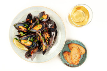 Marinara mussels, moules mariniere, shot from above on a white background with a glass of wine, toasted bread, and a place for text
