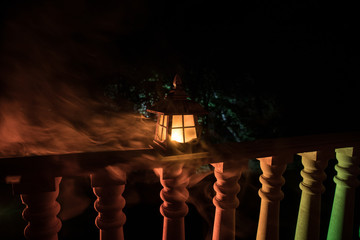 Retro style lantern at night. Beautiful colorful illuminated lamp at the balcony in the garden.