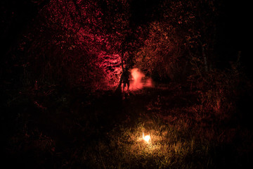 Horror Halloween concept. Burning old oil lamp in forest at night. Night scenery of a nightmare scene.