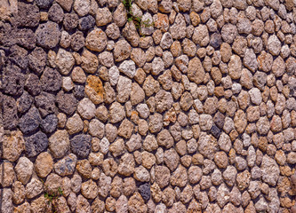 Abstract background – old stone wall exterior, rough brown rock surface texture. 
