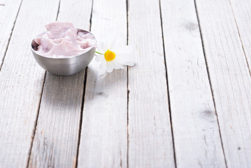 pink cosmetic cream and white herbal flowers on old rusty wooden table background