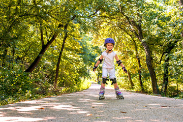 Beautiful smiling girl wearing protection pads and safety helmet enjoying inline roller skating in...