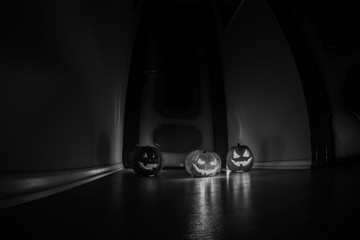 Halloween pumpkin head jack o lantern with glowing candles on background. Pumpkins on wooden floor