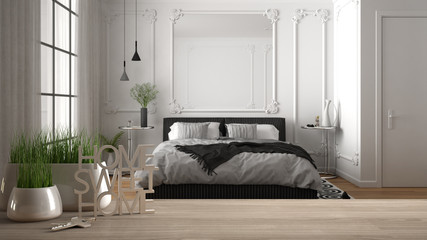 Wooden table, desk or shelf with potted grass plant, house keys and 3D letters home sweet home, over classic bedroom with bed, architecture interior design, copy space background