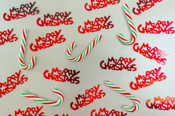  Christmas candies and red shiny lettering Merry Christmas on a silver background. Background for gift paper.