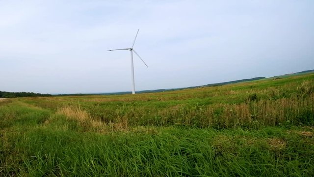 rotating blades of a windmill propeller in field on blue sky background. Wind power generation. Pure green energy.