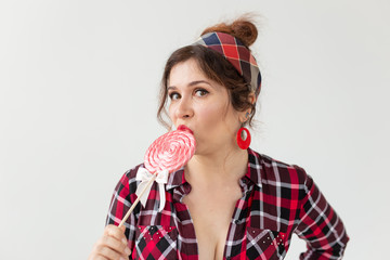 Close up portrait of beautiful young woman eating lollipop over white background