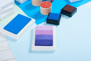 stamp ink pad, lino cutter , papers and rubbers on white wood table