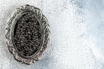 Black caviar in silver bowl on light background