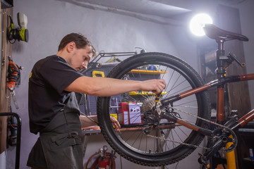 Fototapeta na wymiar Service, repair, bike and people concept - Mechanic repairing a mountain bike in a workshop