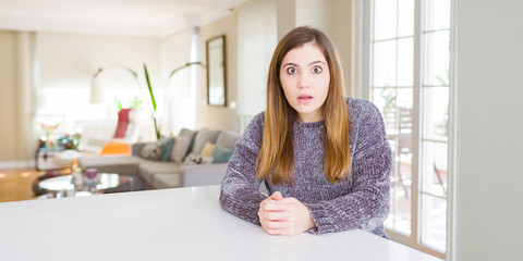 Beautiful young woman at home afraid and shocked with surprise expression, fear and excited face.
