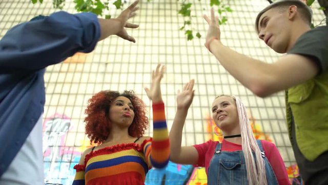 Young multiracial people joining hands, friendship greeting gesture, having fun