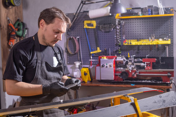 Repair, service and people concept - a man repairing the ski by rubbing a paraffin