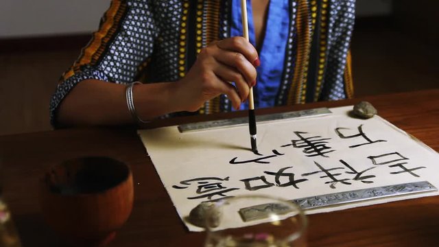 Girl writes Chinese characters (Translation from Chinese Mandarin 1: jixiang ruyi wanshi ankang- to be gratified propitiously with everything in good health, 2: fugui jixiang: wealthy and propitious)