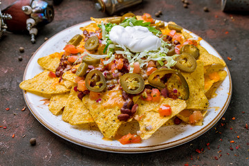 Mexican nachos chips with sauces on dark concrete rustic table