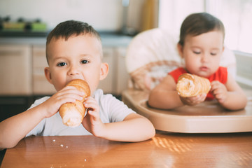 Brother and sister in the kitchen eating tubes with custard or protein cream