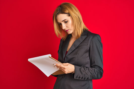 Young beautiful redhead businesswoman wearing suit writing on flip board