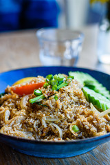 Thai chicken fried rice in a blue bowl on a restaurant table, close up.