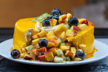 Fresh and tasty fruit cake with grapes, peach, apple, banana and kiwi, closeup